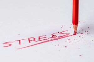 白い紙に力いっぱいSTRESSと書いて先端がつぶれて色が飛び散った赤い色鉛筆